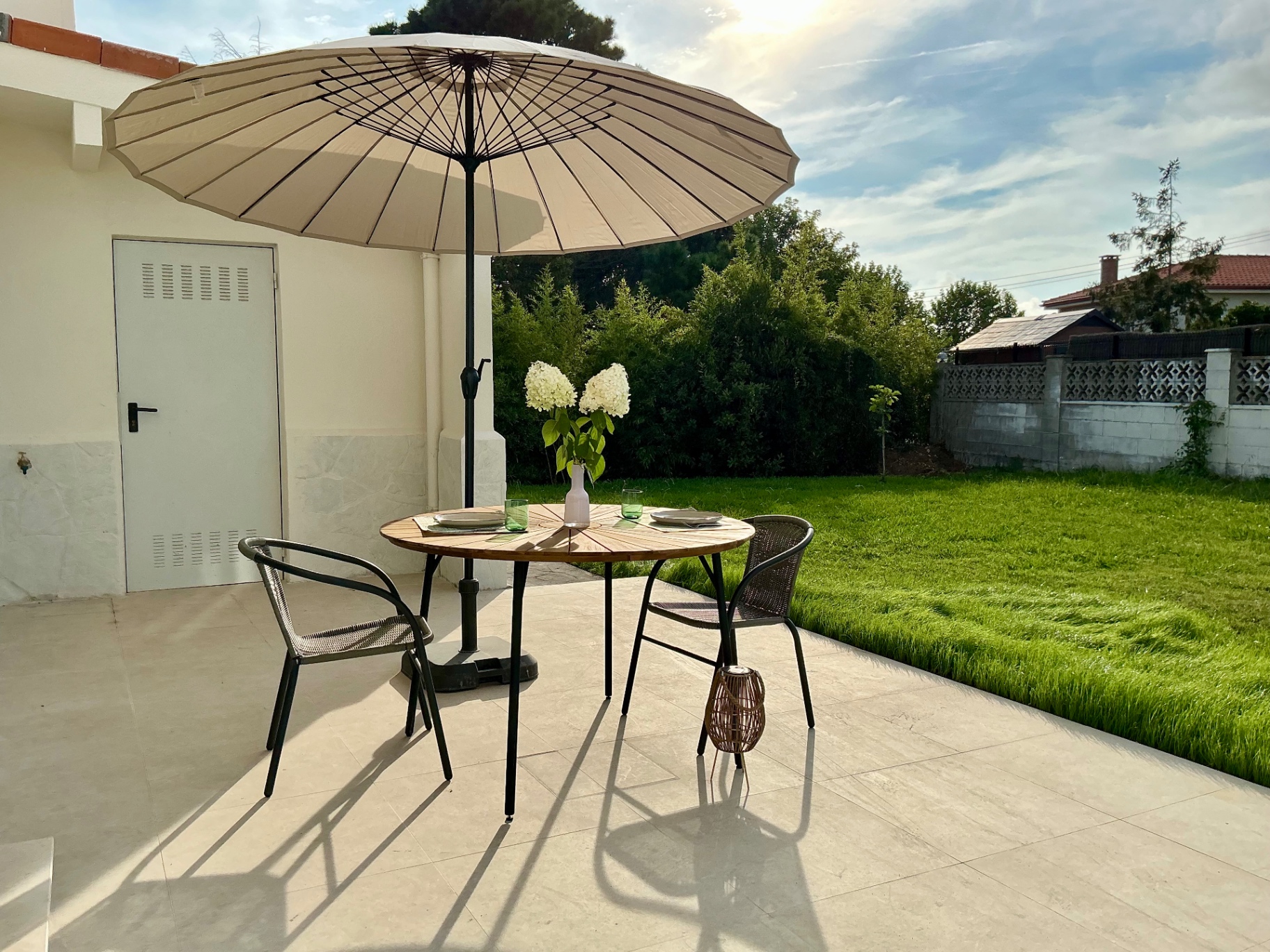 Terraza y jardín con mesa, sillas y parasol