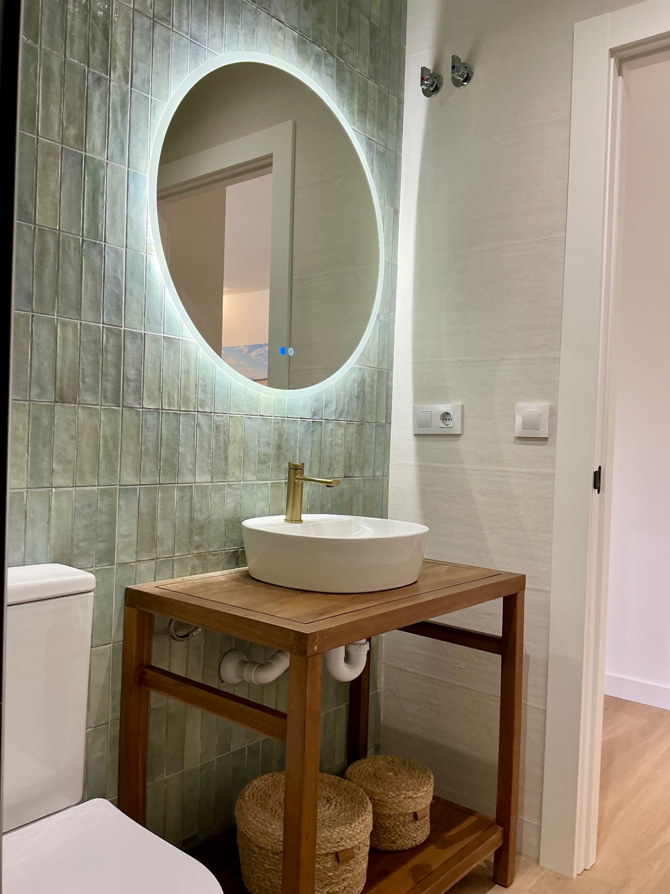 Baño con azulejo verde y lavabo sobre madera